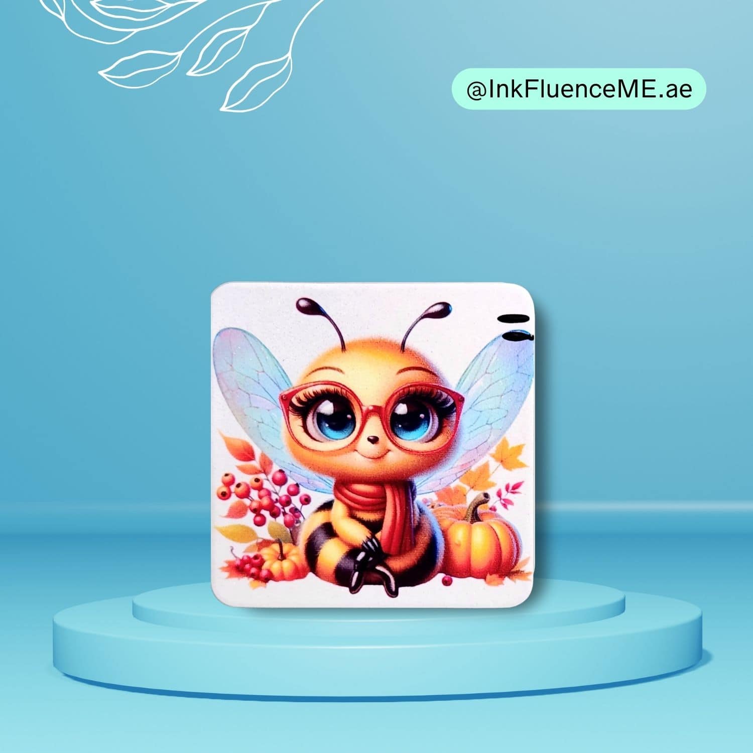 A rounded square magnet with a cute cartoon bee wearing red glasses. The bee is surrounded by autumn leaves and a pumpkin. The magnet is displayed on a light blue background.